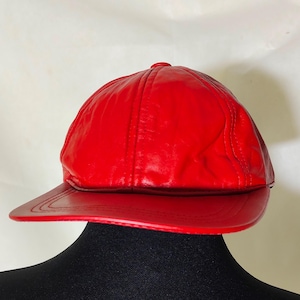 Könnte beinhalten: Eine rote Leder-Baseballkappe mit einem gebogenen Schirm.