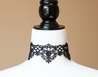 May include: A black lace choker necklace on a white mannequin bust.