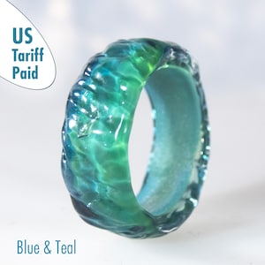 May include: A blue and teal ring with a textured surface. The ring has a wave-like design and the text "Blue & Teal". The words "US Tariff Paid" are also visible.