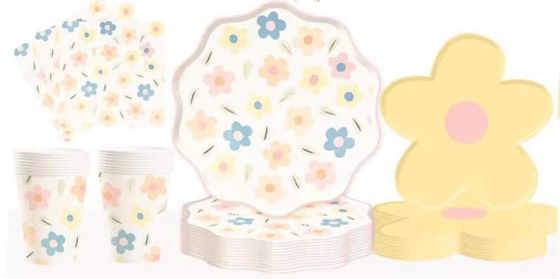 May include: A set of floral-themed party supplies, including plates, cups, and napkins. The plates feature a white background with pastel pink, yellow, and blue flowers. The cups and napkins have a similar design. The plates are stacked in a pile, and the cups and napkins are arranged in a row.