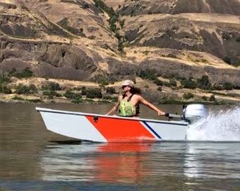 May include: A person in a life vest is driving a small white and orange boat with a blue stripe on the side. The boat has a small outboard motor and is creating a spray of water as it moves through the water.