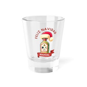 May include: A clear shot glass featuring the words "Feliz Navidad" and a cartoon tequila bottle wearing a Santa hat. The bottle has a winking face and the name "Manuel" on a red banner below.