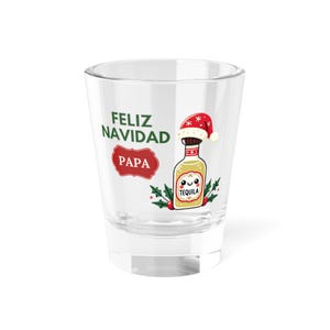 May include: A clear shot glass with the words "FELIZ NAVIDAD PAPA" in green and red. A cartoon tequila bottle wearing a Santa hat is featured on the glass, along with holly sprigs. The word "TEQUILA" is on the bottle.