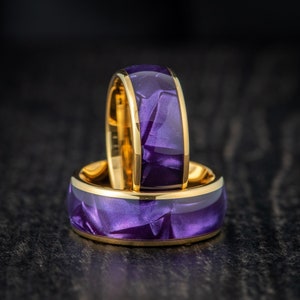 May include: Two gold rings with a purple iridescent finish. The rings are stacked on top of each other.