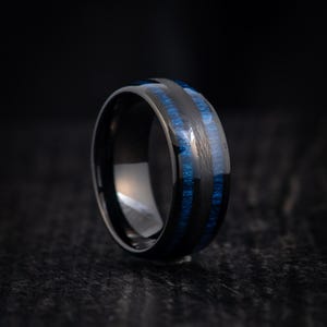 May include: A black tungsten carbide ring with blue wood inlay. The ring has a polished finish and a comfortable fit.