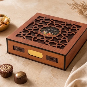 May include: A wooden box with a decorative cutout design on the lid. The box is brown with a gold accent and contains chocolates. A small bowl of nuts is also visible.