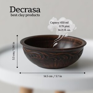 Pode incluir: Uma tigela de argila marrom escura artesanal com desenhos florais em relevo. A tigela tem 14,5 cm de diâmetro e 5,5 cm de altura, com capacidade para 450 ml. O texto "Decrasa best clay products" é visível.