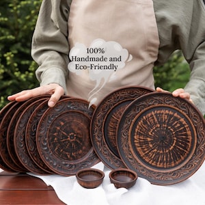 May include: A collection of handmade, eco-friendly brown ceramic plates and small bowls. The plates feature a decorative floral border and a unique wood-grain pattern in the center. The text "100% Handmade and Eco-Friendly" is visible.