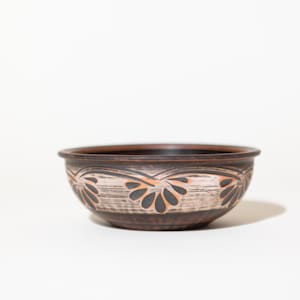 Peut inclure: Un bol en céramique brun avec un motif décoratif de fleurs noires et orange.
