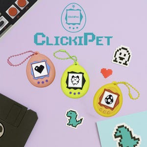 May include: Three retro-style ClickiPet virtual pet keychains in peach, yellow, and gold. Each has a pixelated pet display. The image includes pixel art stickers of a ghost, heart, and dinosaur, plus the ClickiPet logo and text.