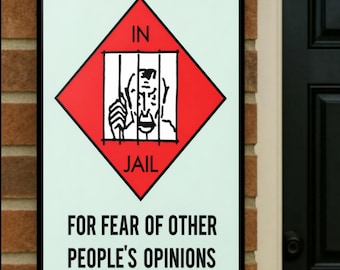 May include: A rectangular sign with a black border. The sign has a light green background with a red diamond in the center. Inside the diamond is a black and white illustration of a person behind jail bars. The words "IN" and "JAIL" are above and below the illustration. Below the diamond, the sign reads "FOR FEAR OF OTHER PEOPLE'S OPINIONS."