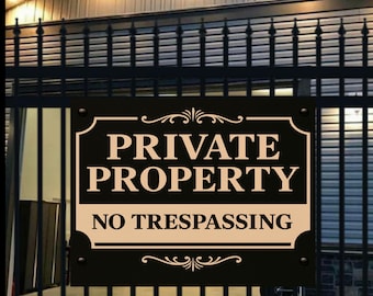 Könnte beinhalten: Ein schwarzes rechteckiges Schild mit den Worten "PRIVATE PROPERTY" und "NO TRESPASSING" in cremefarbener Schrift. Das Schild ist an einem schwarzen Metallzaun befestigt.
