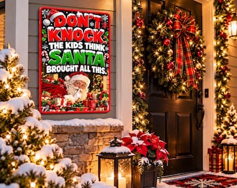 May include: A rectangular sign with a red border featuring the text DON'T KNOCK THE KIDS THINK SANTA BROUGHT ALL THIS in white, red, and green lettering. The sign displays an illustration of Santa Claus holding a finger to his lips.