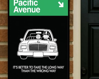 May include: A black sign with the words "Pacific Avenue" in white on a green background. Below, a white car graphic with a Monopoly character and dice is displayed. The text "IT'S BETTER TO TAKE THE LONG WAY THAN THE WRONG WAY" is at the bottom.