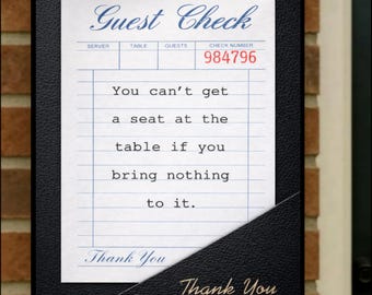 Könnte beinhalten: Ein schwarzer, texturierter Gästescheckhalter mit einem weißen Gästescheck mit blauen Linien und dem Text: Guest Check, 984796, You can't get a seat at the table if you bring nothing to it. Thank You. Der Halter trägt die goldene Aufschrift Thank You.