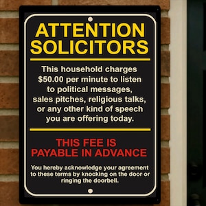 Könnte beinhalten: Ein rechteckiges schwarzes Schild mit weißem und gelbem Text mit der Aufschrift "ATTENTION SOLICITORS". Das Schild gibt eine Gebühr für das Anhören verschiedener Arten von Reden an, wobei die Gebühr im Voraus zu entrichten ist. Das Schild ist an einer Ziegelmauer angebracht.