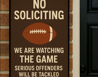 May include: A rectangular brown sign with white text and a football graphic. The sign reads "NO SOLICITING" above a brown football with white stripes. Below the football, it says "WE ARE WATCHING THE GAME. SERIOUS OFFENDERS WILL BE TACKLED."