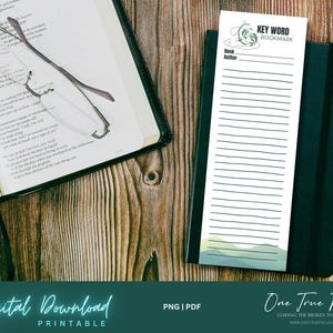 Può includere: Un segnalibro bianco con il testo "KEY WORD BOOKMARK" e linee per appunti, appoggiato su un taccuino nero. Un paio di occhiali e un libro aperto sono anche su una superficie di legno. L'immagine contiene anche il testo "Digital Download Printable".