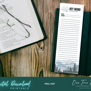 Può includere: Un segnalibro stampabile con una scena di montagna ad acquerello e uno spazio per scrivere parole chiave, titolo del libro e autore. Il segnalibro è etichettato "Key Word Bookmark" e "One True Focus".