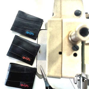 Puede incluir: Tres carteras de cuero negro con la palabra "urchin" impresa en ellas en diferentes colores. Las carteras est&aacute;n sobre una superficie blanca junto a un par de tijeras plateadas y una m&aacute;quina de coser.