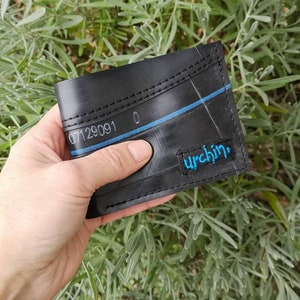 Puede incluir: Cartera de cuero negro hecha de c&aacute;mara de bicicleta reciclada con costuras azules y la palabra "urchin" en letras azules.