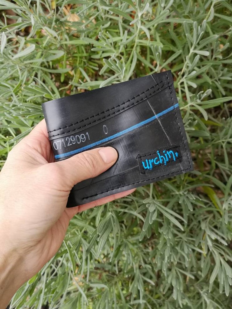 Puede incluir: Cartera de cuero negro hecha de c&aacute;mara de bicicleta reciclada con costuras azules y la palabra "urchin" en letras azules.