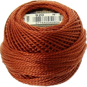 May include: A ball of DMC embroidery floss in color 920, a deep orange-brown shade. The label reads "DMC N° 920" and includes a barcode. The floss is made of cotton.