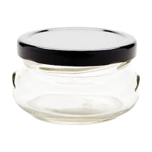May include: A clear glass jar with a black lid. The jar has a rounded shape with small handles on the sides. The lid is shiny and the jar is empty.