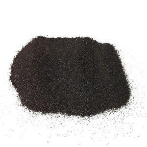 May include: A close-up of a pile of black sand. The sand is fine-grained and has a slightly rough texture.