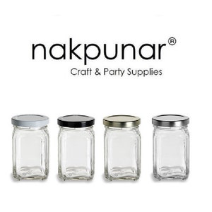 May include: Four clear glass jars with different colored lids. The lids are white, black, silver, and gold. The jars are square shaped and have a wide mouth opening. The jars are all empty and are sitting on a white surface. The text "nakpunar® Craft & Party Supplies" is above the jars.