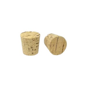 Puede incluir: Dos tapones de botella de corcho natural. Los tapones están hechos de corcho natural y tienen una textura ligeramente rugosa. Ambos tienen forma cilíndrica y un diámetro de aproximadamente 2,5 cm.