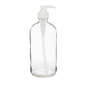 May include: Clear glass soap dispenser with a white plastic pump. The bottle has a rounded shape and a wide base. The pump is positioned at the top of the bottle and has a curved spout. The dispenser is designed for liquid soap or lotion.