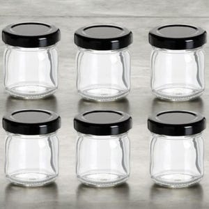 Puede incluir: Seis tarros de vidrio transparentes con tapas negras. Los tarros son pequeños y redondos, y son perfectos para guardar objetos pequeños como especias, hierbas o manualidades.