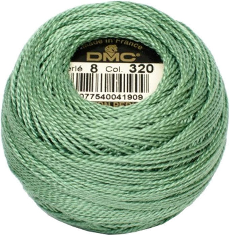 May include: A ball of DMC Perle cotton thread in a soft green color, labeled with "8 Col. 320" and a barcode. The thread is tightly wound, showing the texture of the fibers. Made in France.