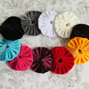 May include: Assortment of 10 round fabric covered buttons in various colors, including black, gray, white, turquoise, pink, maroon, red, yellow, and orange. The buttons are all the same size and have a ruffled texture.