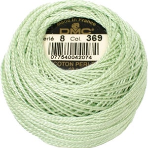 May include: A ball of light green DMC Perle cotton thread, color 369, with a label indicating it's made in France. The thread is tightly wound, showing the texture of the cotton. Ideal for embroidery and needlework projects.