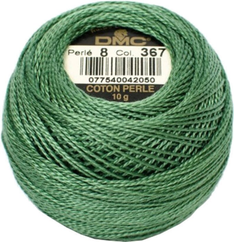 May include: A ball of green DMC Perl&eacute; cotton thread, Col. 367, 10 g. The label includes a barcode and the text "COTON PERLE". The thread is tightly wound, showing the texture of the yarn. Ideal for embroidery and other needlecraft projects.