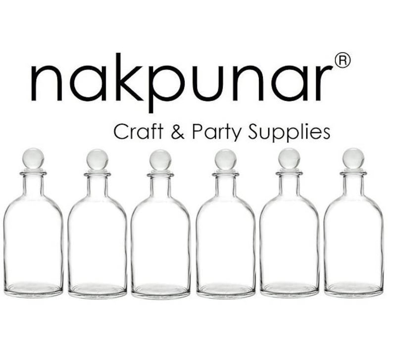 Puede incluir: Seis botellas de vidrio transparente con tapones esf&eacute;ricos dispuestas en fila. Las botellas est&aacute;n vac&iacute;as y tienen una forma cl&aacute;sica. El texto "nakpunar Craft & Party Supplies" est&aacute; arriba.