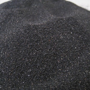 May include: A close-up of black sand, showing the individual grains of sand.