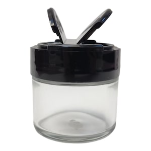 May include: A clear glass jar with a black lid that has two hinged openings. The lid is designed to allow for easy dispensing of spices or other dry ingredients.