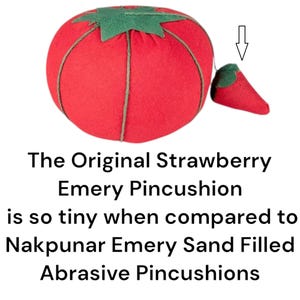 Puede incluir: Un alfiletero en forma de fresa roja y verde con un peque&ntilde;o alfiletero en forma de fresa roja unido al lado. El texto "The Original Strawberry Emery Pincushion is so tiny when compared to Nakpunar Emery Sand Filled Abrasive Pincushions" est&aacute; debajo de la imagen.
