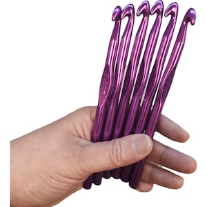 Puede incluir: Conjunto de seis agujas de crochet de color morado, cada una mide 10,0 mm. Las agujas se sostienen en una mano.