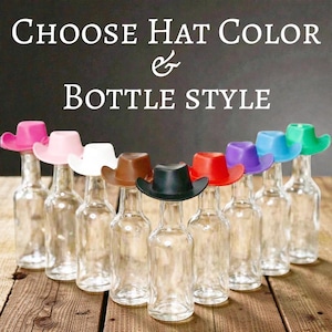 May include: A collection of clear glass bottles, each adorned with a miniature cowboy hat in a range of colours: pink, white, brown, black, red, purple, blue, and green. The text "CHOOSE HAT COLOR & BOTTLE STYLE" is visible.