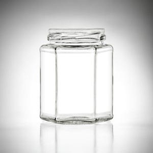 May include: A clear glass hexagonal jar with a wide mouth opening. The jar is empty and has a smooth, polished surface.
