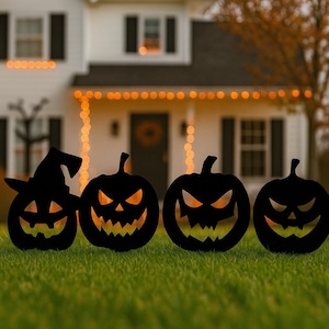 May include: Four black Halloween pumpkin lawn decorations with carved faces and a witch hat. The pumpkins are silhouetted against a house with string lights and a green lawn.