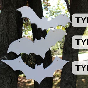 Op de afbeelding: Drie witte houten vleermuis uitsnijdingen van verschillende groottes hangen aan een boomstam. De uitsnijdingen zijn gelabeld "TYPE 1", "TYPE 2" en "TYPE 3".