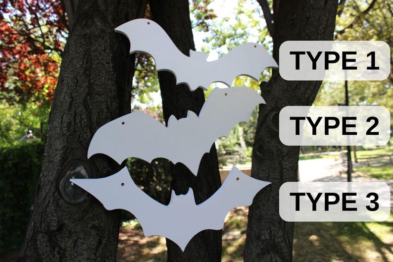 Op de afbeelding: Drie witte houten vleermuis uitsnijdingen van verschillende groottes hangen aan een boomstam. De uitsnijdingen zijn gelabeld "TYPE 1", "TYPE 2" en "TYPE 3".
