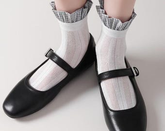 May include: White socks with a black and white gingham ruffle trim, worn with black leather mary jane shoes.
