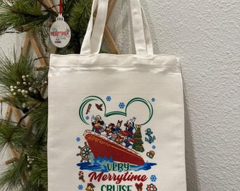 May include: A white canvas tote bag featuring a colorful graphic of a cruise ship with cartoon characters and the text "Very Merrytime Cruise." The bag has two long handles and is hanging against a white wall.