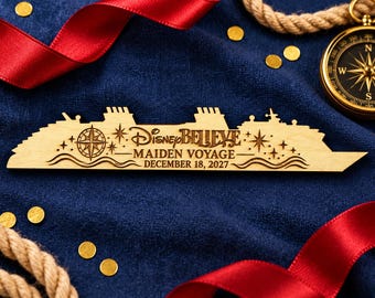 May include: A light-colored wooden cutout shaped like a cruise ship, engraved with the text Disney BELIEVE MAIDEN VOYAGE DECEMBER 18, 2027, a compass rose, and star accents. The design features wavy lines along the bottom edge.